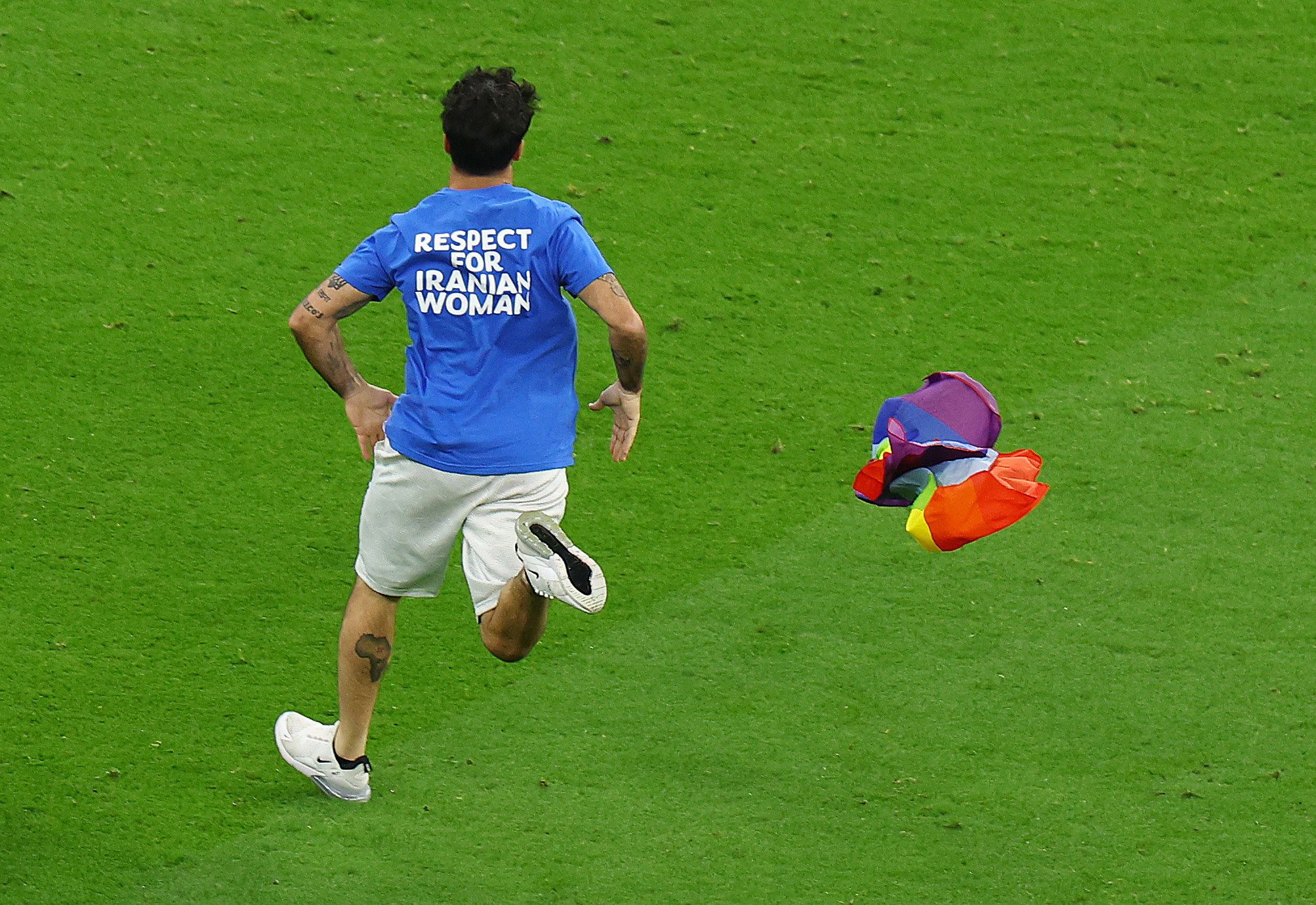 A jimmy jump runs onto the pitch wearing a t-shirt with a message saying 'Respect for Iranian Women' and holding a rainbow flag during the match between Portugal and Uruguay on November 28, 2022. 