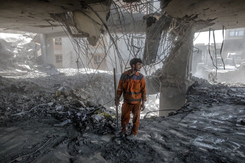 A worker standing amid the rubbles of a building destroyed in Israeli attacks, Tehran, Iran