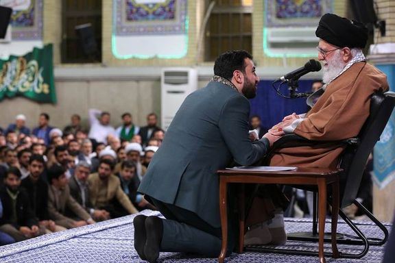 Khamenei seen with a religious singer kneeling in front of him. Undated
