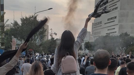 A woman taking off her headscarf during a protest in Iran