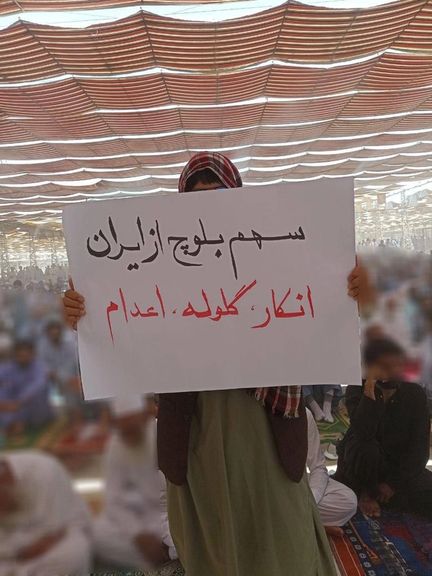 A protester holds a placard that reads “Negligence, Bullets, Execution is the share of Baluch people in Iran” during Friday prayers in the city of Zahedan on June 16, 2023.
