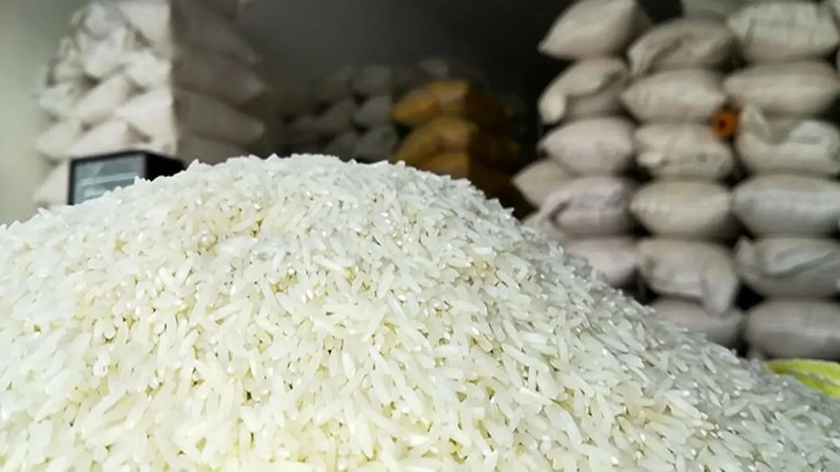A pile of rice with stacked bags of rice in the background, in a warehouse in Iran. (Undated)