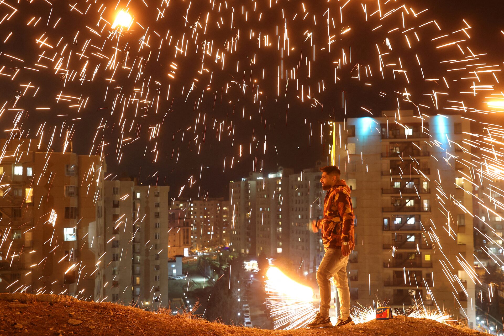An Iranian man lights a firework during the Wednesday Fire celebration (Chaharshanbeh Suri in Persian) at a park in Tehran, Iran. (2024)