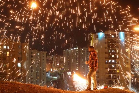 An Iranian man lights a firework during the Wednesday Fire celebration (Chaharshanbeh Suri in Persian) at a park in Tehran, Iran. (2024)