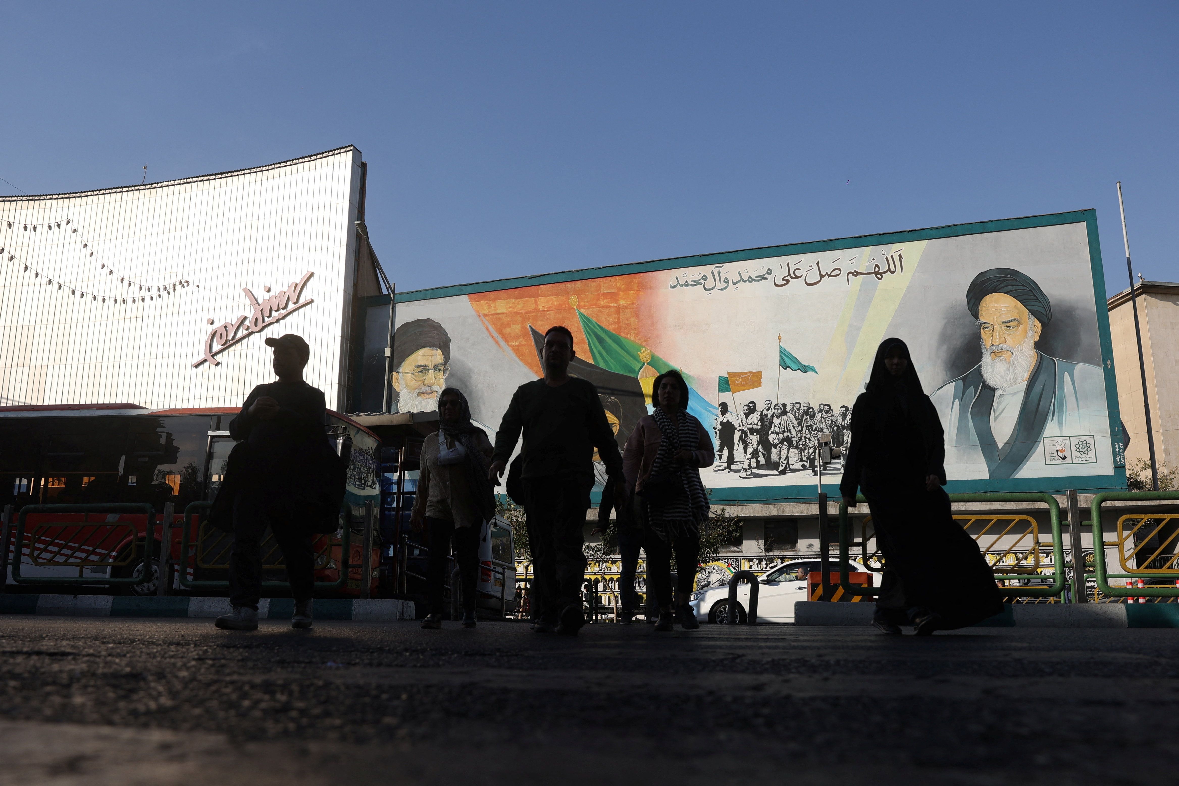 People walk next to a mural with a picture of Iran's Supreme Leader, Ali Khamenei, on a street in Tehran, Iran, November 5, 2025. 