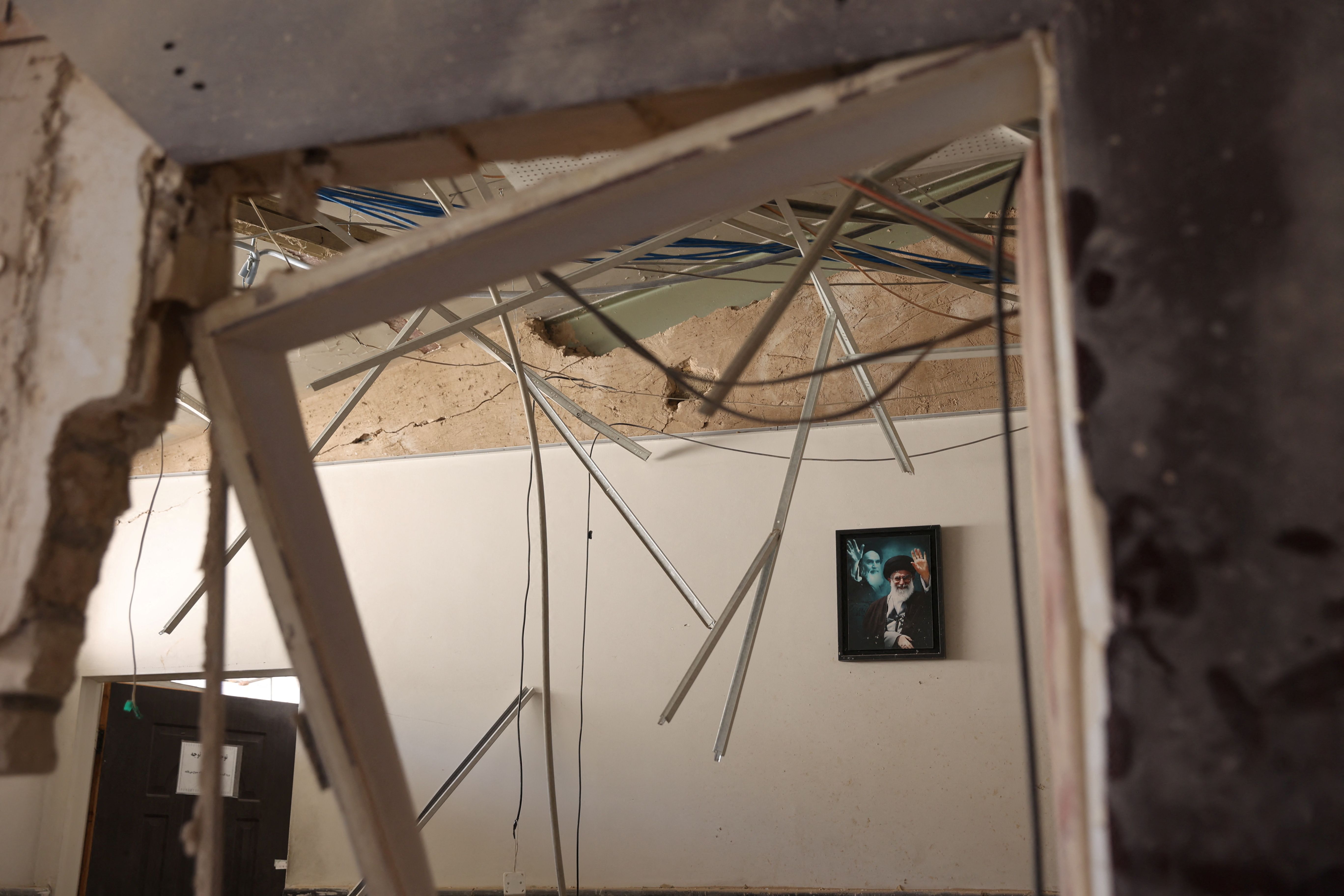 A picture depicting Iran's late Supreme Leaders Ali Khamenei and Ruhollah Khomeini hangs on a wall, following an Israeli strike on Evin Prison that took place on June 23, 2025. 