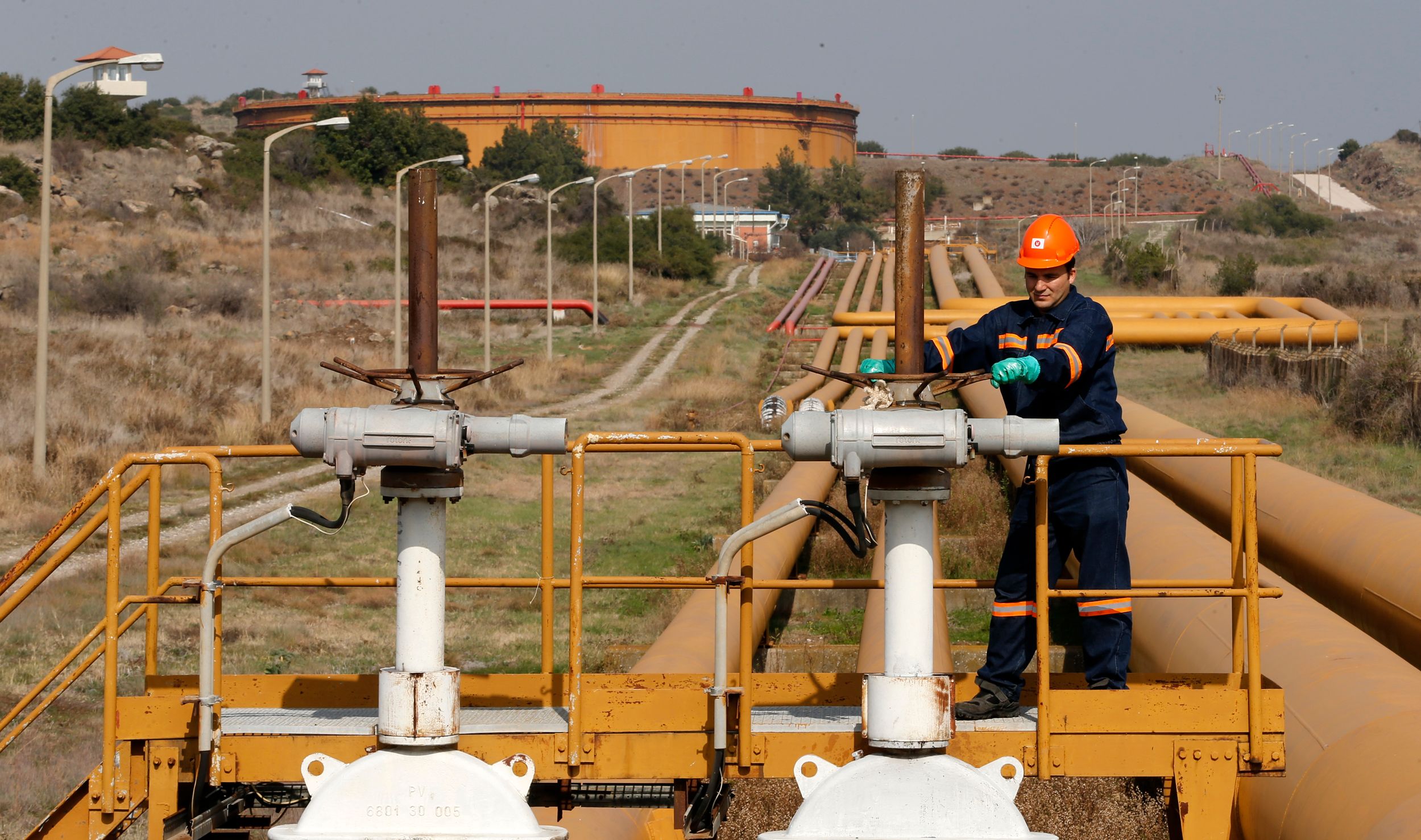 A worker checks the valve gears of pipes linked to oil tanks at Turkey's Mediterranean port of Ceyhan, which is run by state-owned Petroleum Pipeline Corporation (BOTAS), some 70 km (43.5 miles) from Adana February 19, 2014. 