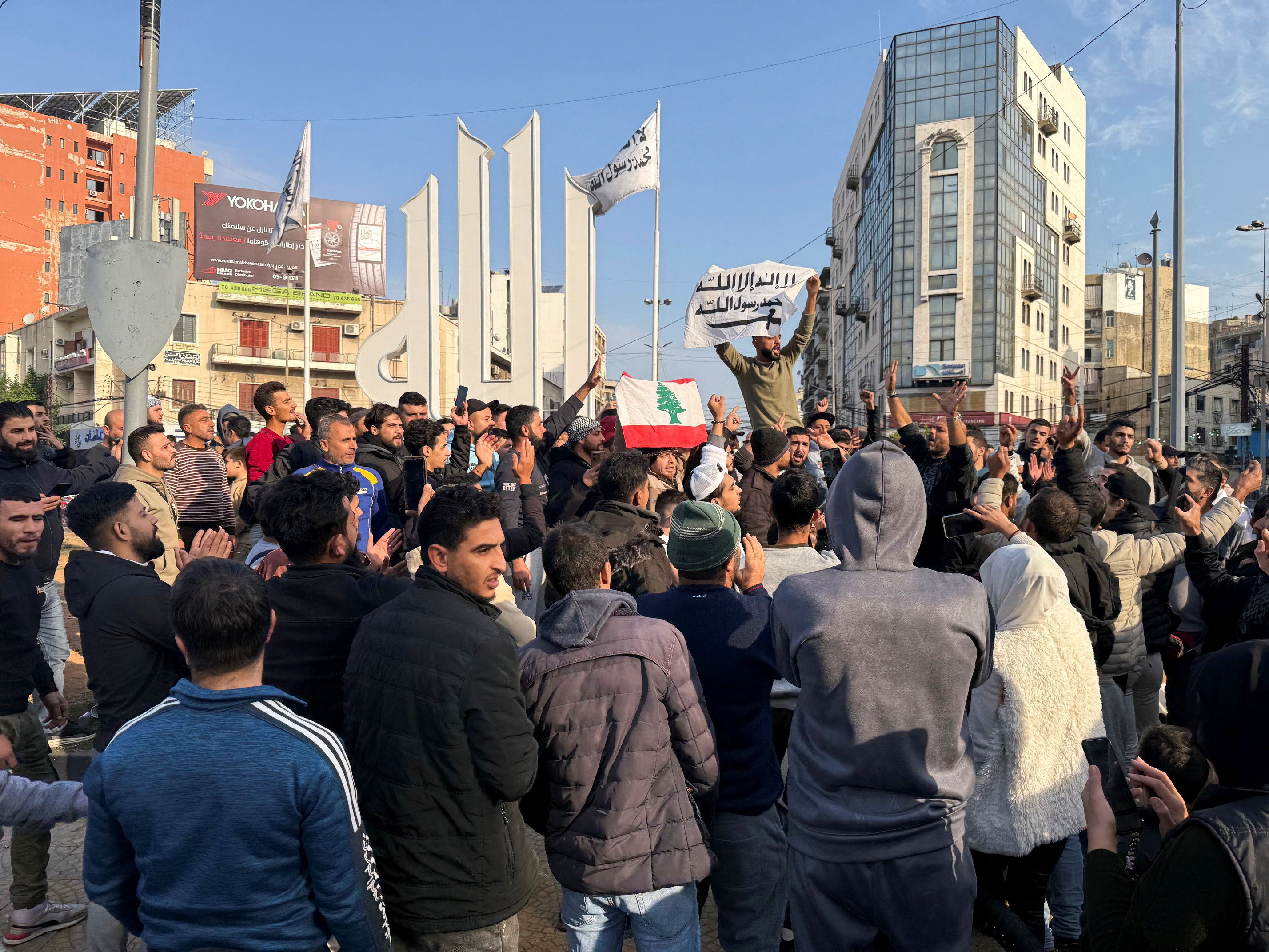 People gesture as a man holds the Syrian opposition flag, after Syrian rebels announced that they have ousted President Bashar al-Assad, in Tripoli, northern Lebanon December 8, 2024.