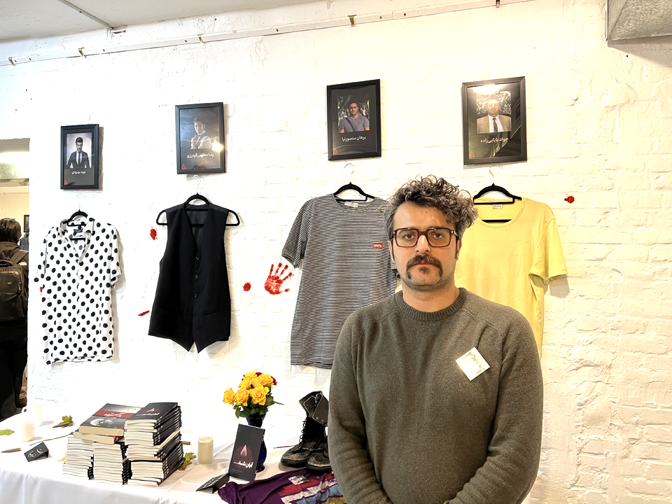 The brother of slain protestor Borhan Mansournia standing next to Borhan's shirt 