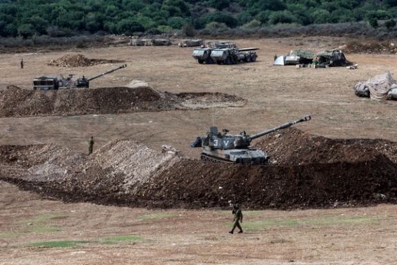 An Israeli soldier walks past a tank near Israel's border with Lebanon, northern Israel, October 9.