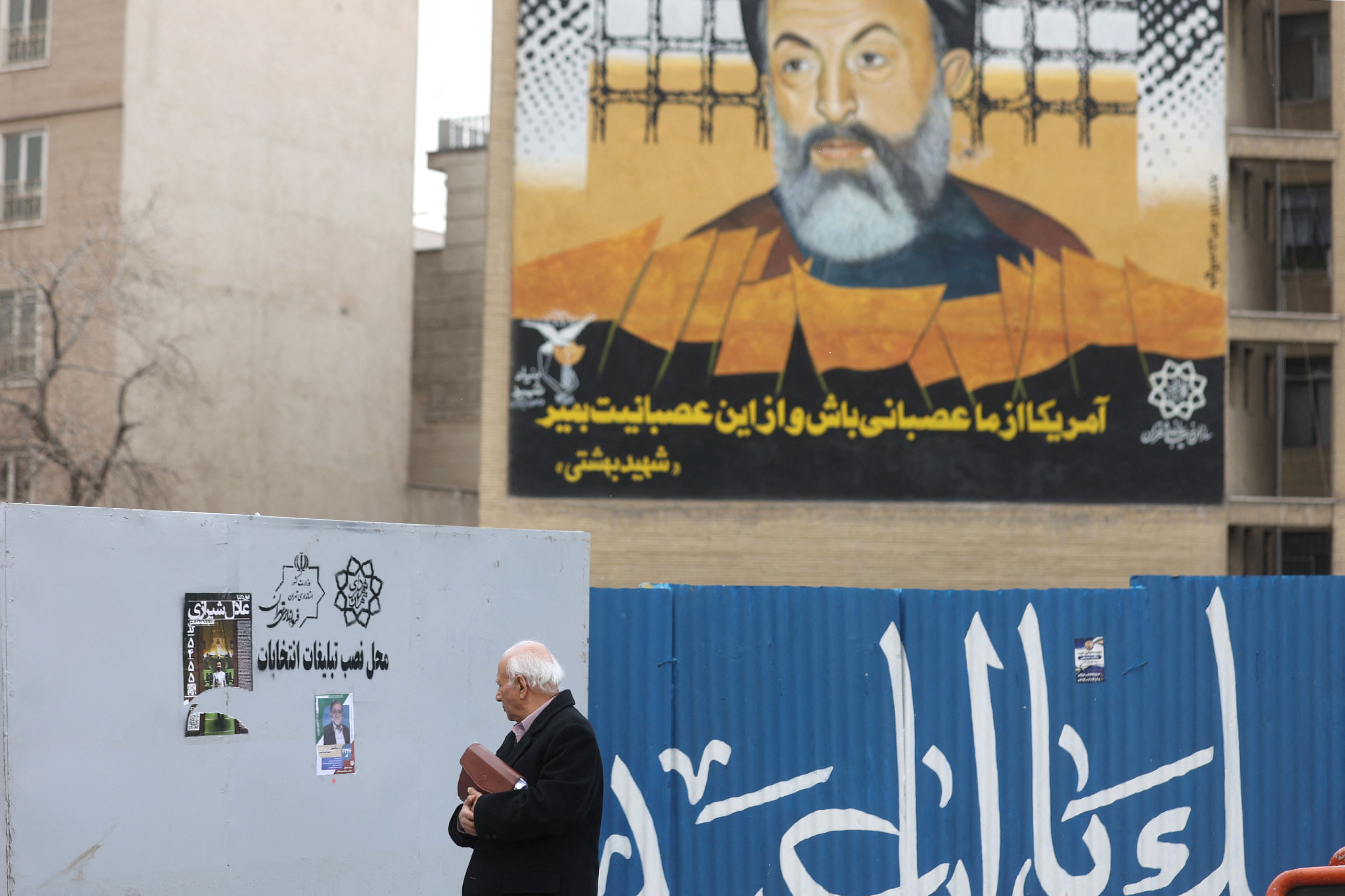 An Iranian man walks past campaign posters for the parliamentary election in Tehran, Iran, February 27, 2024.