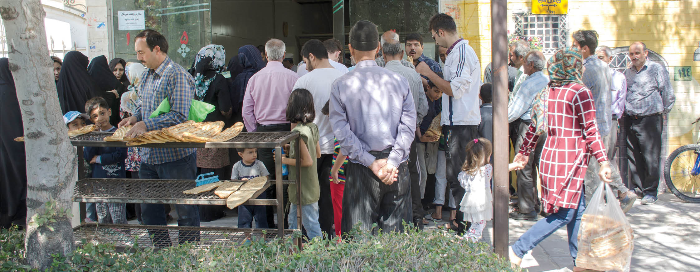 Iranians stand in line outside a bakery  