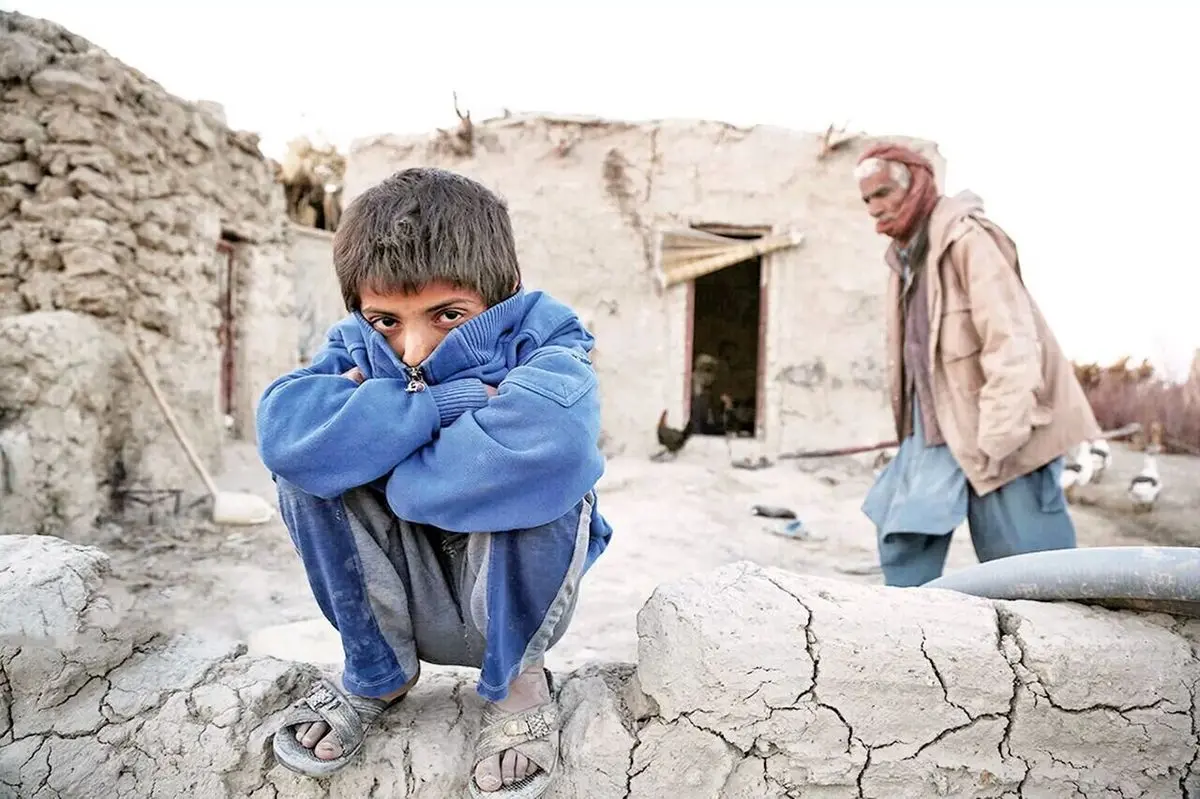 A young boy sits quietly in front of a mud-brick home in Sistan and Baluchestan. (undated)