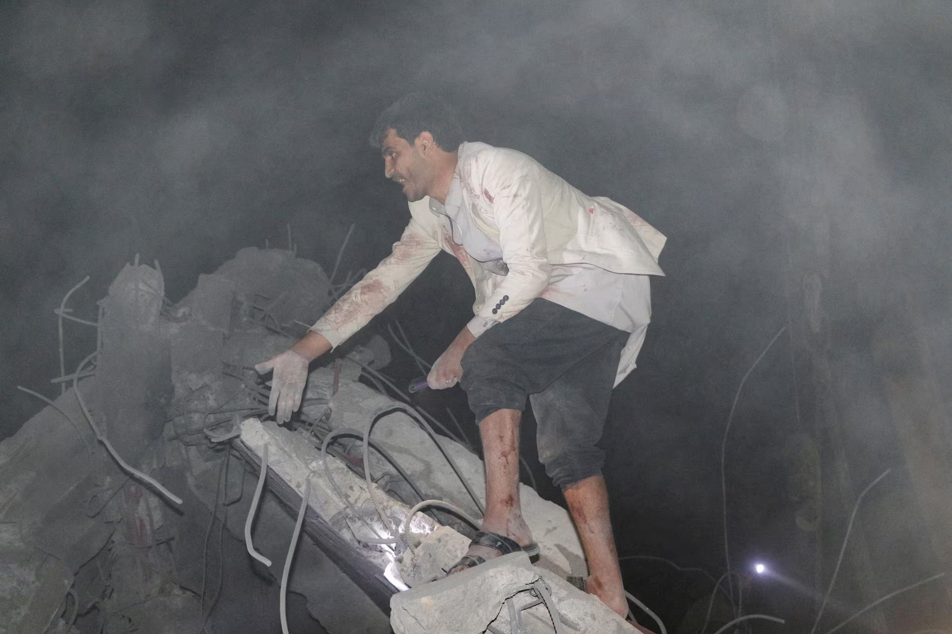 A man gestures as he searches in the rubble of a house hit by a US strike in Saada, Yemen