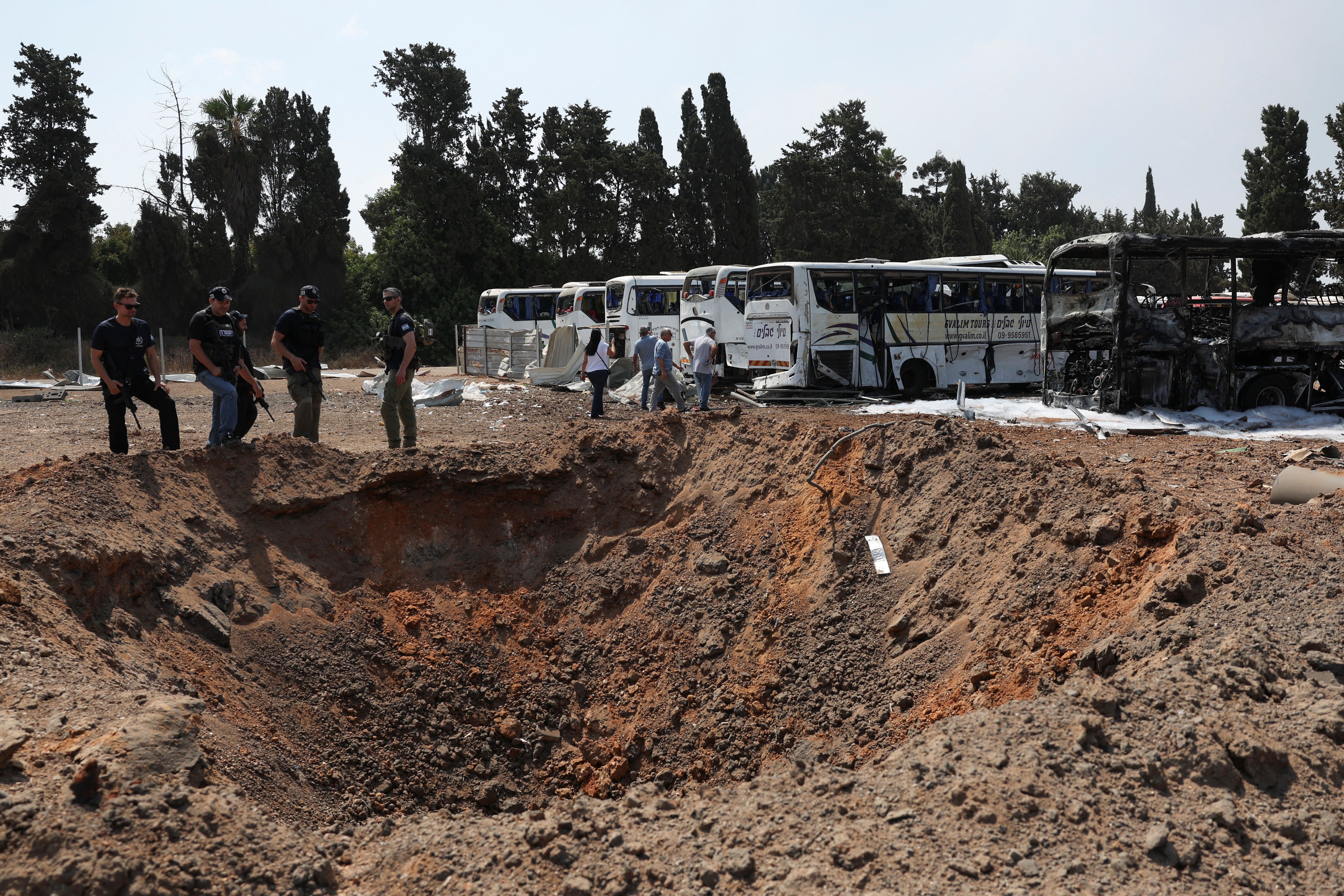 Police officers stand next to a crater at an impact site following a missile attack from Iran, in Herzliya, Israel, June 17, 2025. 