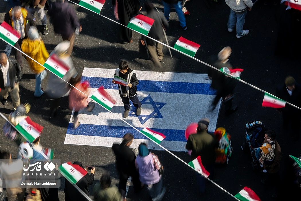 A boy stands on an Israeli flag painted on a street during regime-sponsored demonstrations to mark the 45th anniversary of Islamic Republic establishment, Tehran, February 11, 2024 