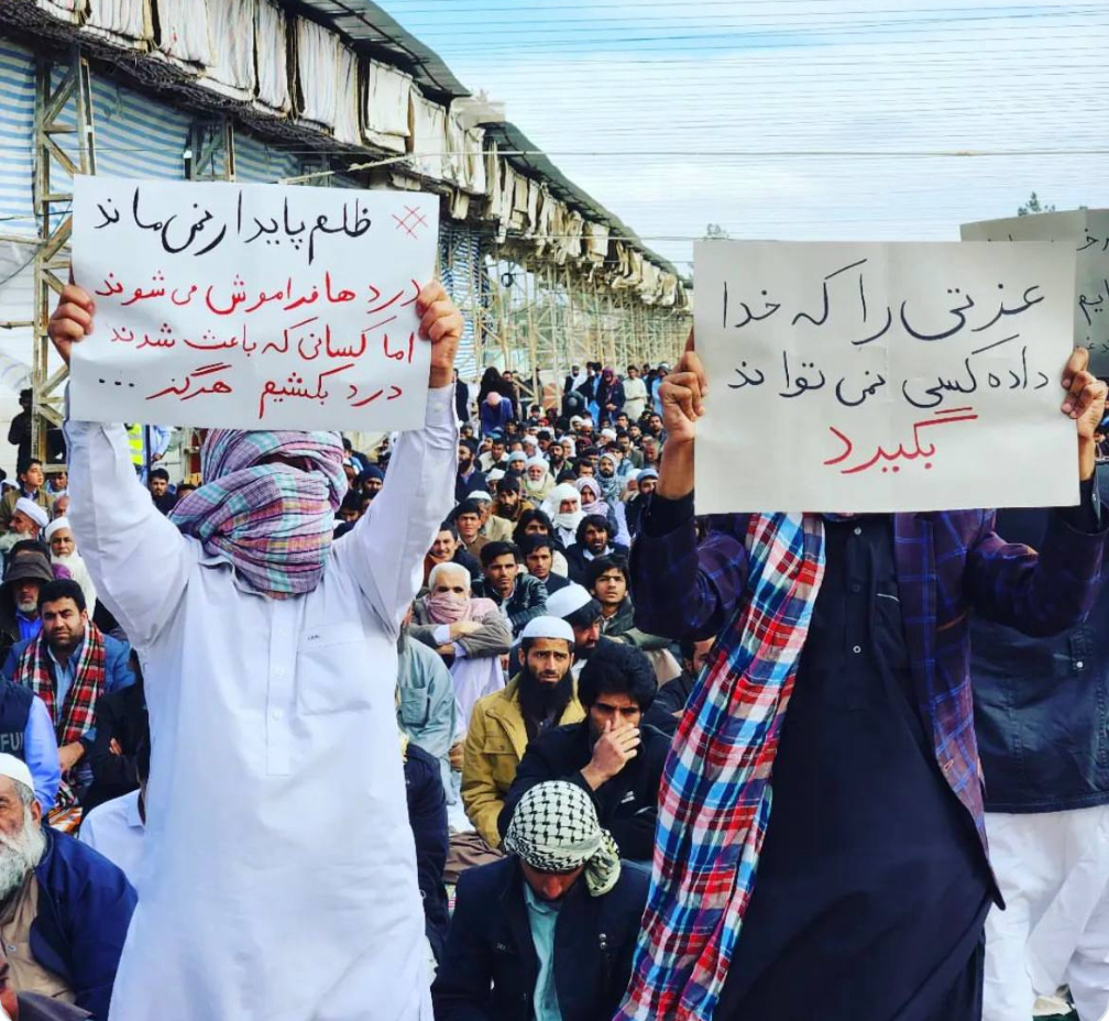 People in Zahedan carrying placards. One message says, "Oppression cannot last"