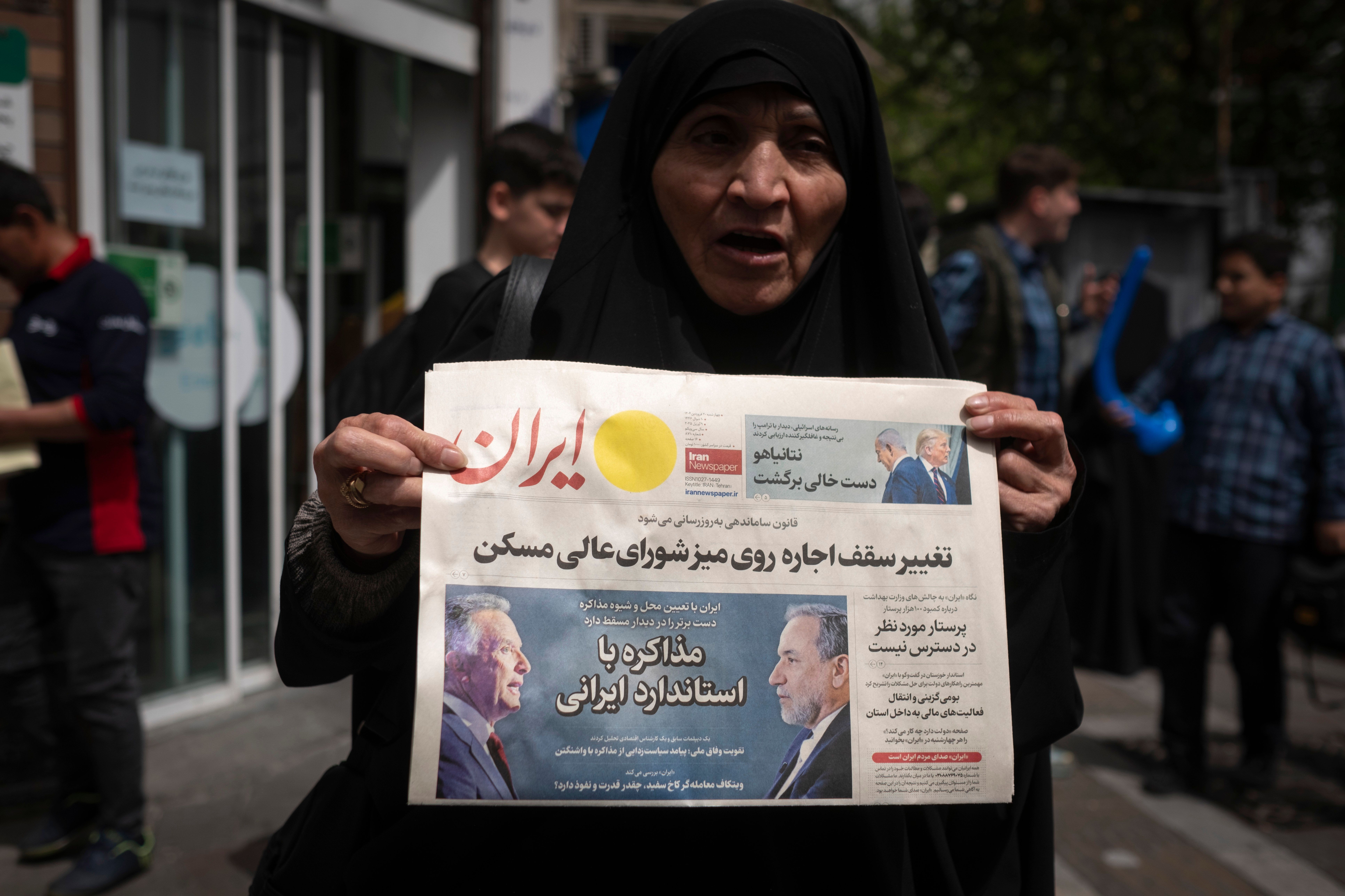 A veiled Iranian woman holds a newspaper featuring portraits of Iranian Foreign Minister Abbas Araghchi and Steve Witkoff, White House special envoy, while she shows her protest against Iran and US negotiations in downtown Tehran, Iran, on April 9, 2025. 