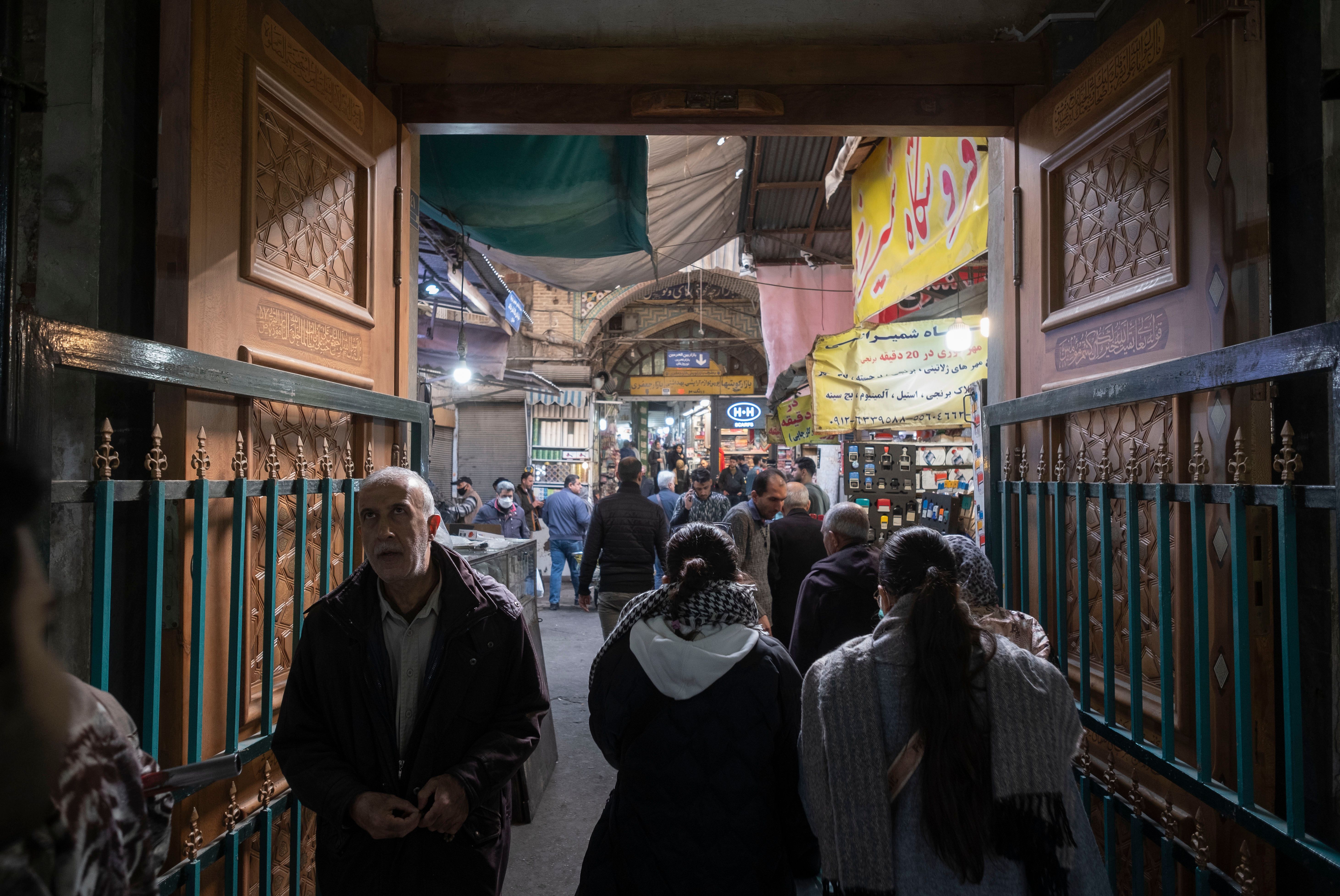 An Iranian man and two women walk along a corridor in Tehran Grand Bazaar (Market), December 3, 2022.