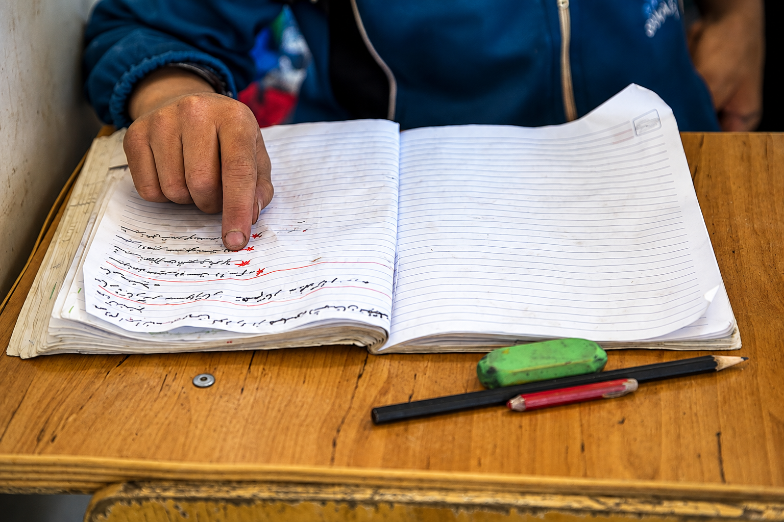 A student points to writing in a notebook at a school in Iran. (undated)