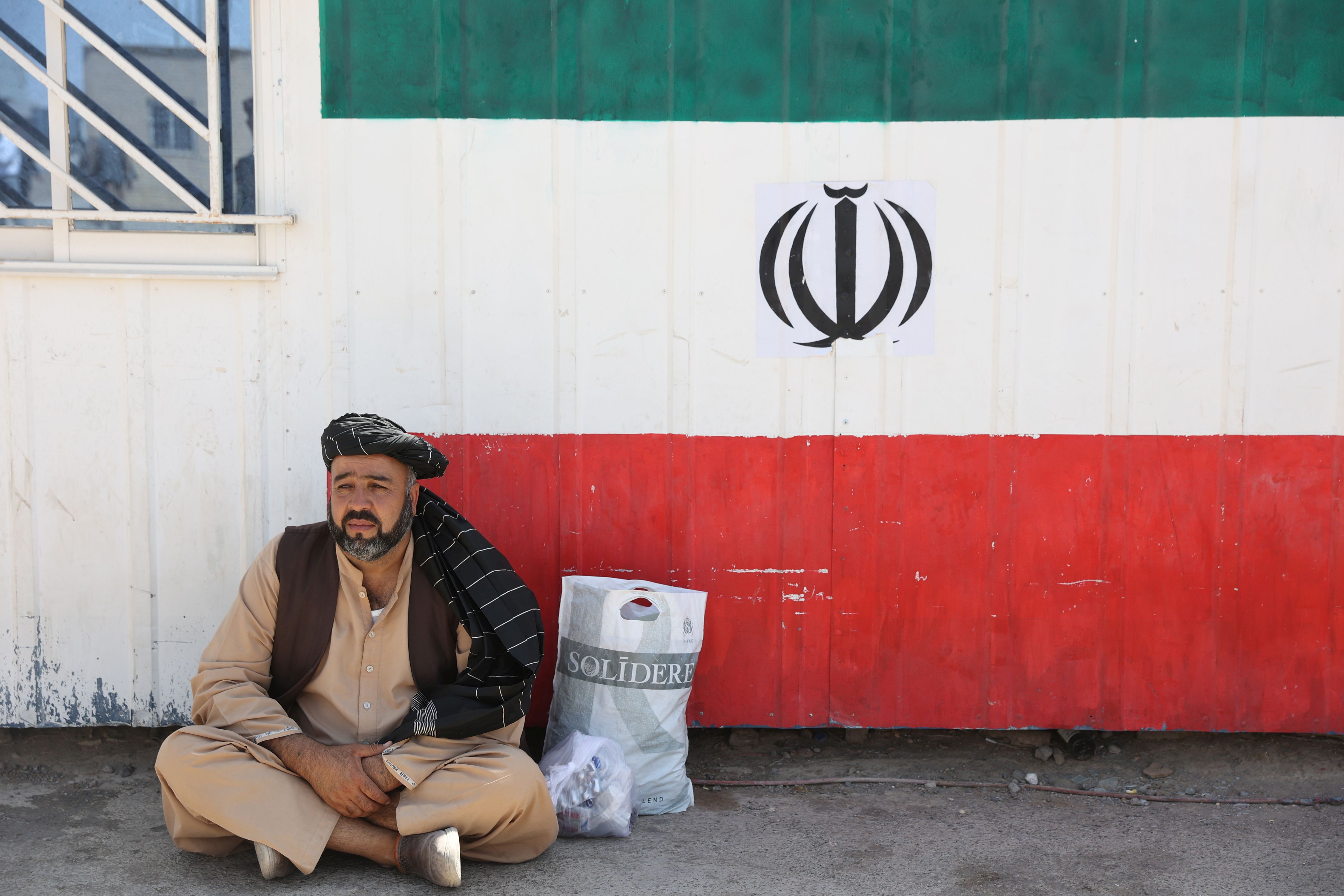 An Afghan man sits at the Dowqarun border crossing between Iran and Afghanistan, Razavi Khorasan Province, Iran August 29, 2021.