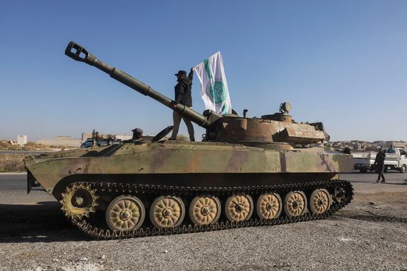 A rebel fighter stands atop of a military vehicle as he carries a Hayat Tahrir al-Sham flag in Saraqeb town in northwestern Idlib province, Syria December 1, 2024.