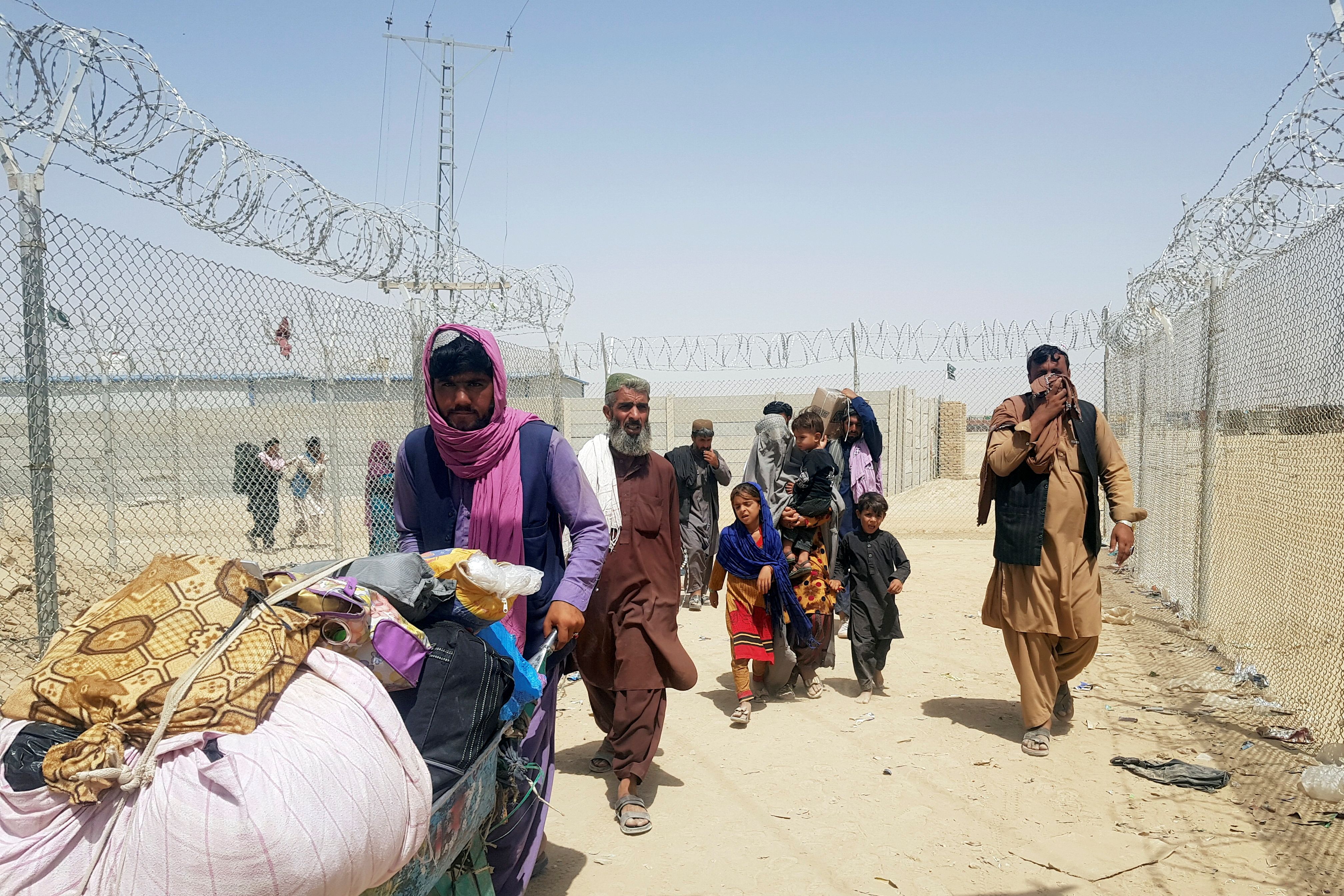 A family from Afghanistan walk next to fence to cross into Pakistan at the Friendship Gate crossing point, in the Pakistan-Afghanistan border town of Chaman, Pakistan September 6, 2021. 