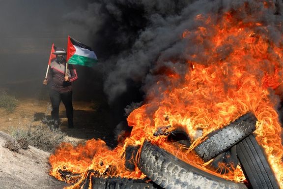 A Palestinian holds flags during a protest against Israeli army raid in Jenin, along Israel-Gaza border fence east of Gaza City July 3, 2023.