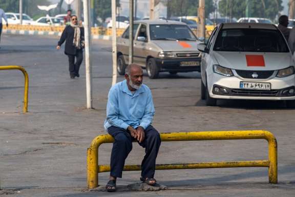 An elderly man sits on a metal railing at a taxi station in the southern Iranian city of Ahvaz, August 25, 2025.