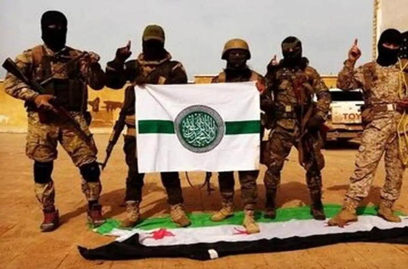 اعضا حرکت مجاهدین اهل سنت ایران که پرچم خود را دست گرفته و پرچم استقلال سوریه را زیر پا گذاشته‌اند