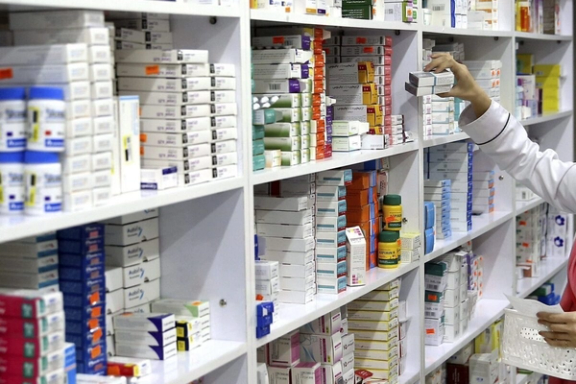 A pharmacist organizes medications on shelves in an Iranian pharmacy.