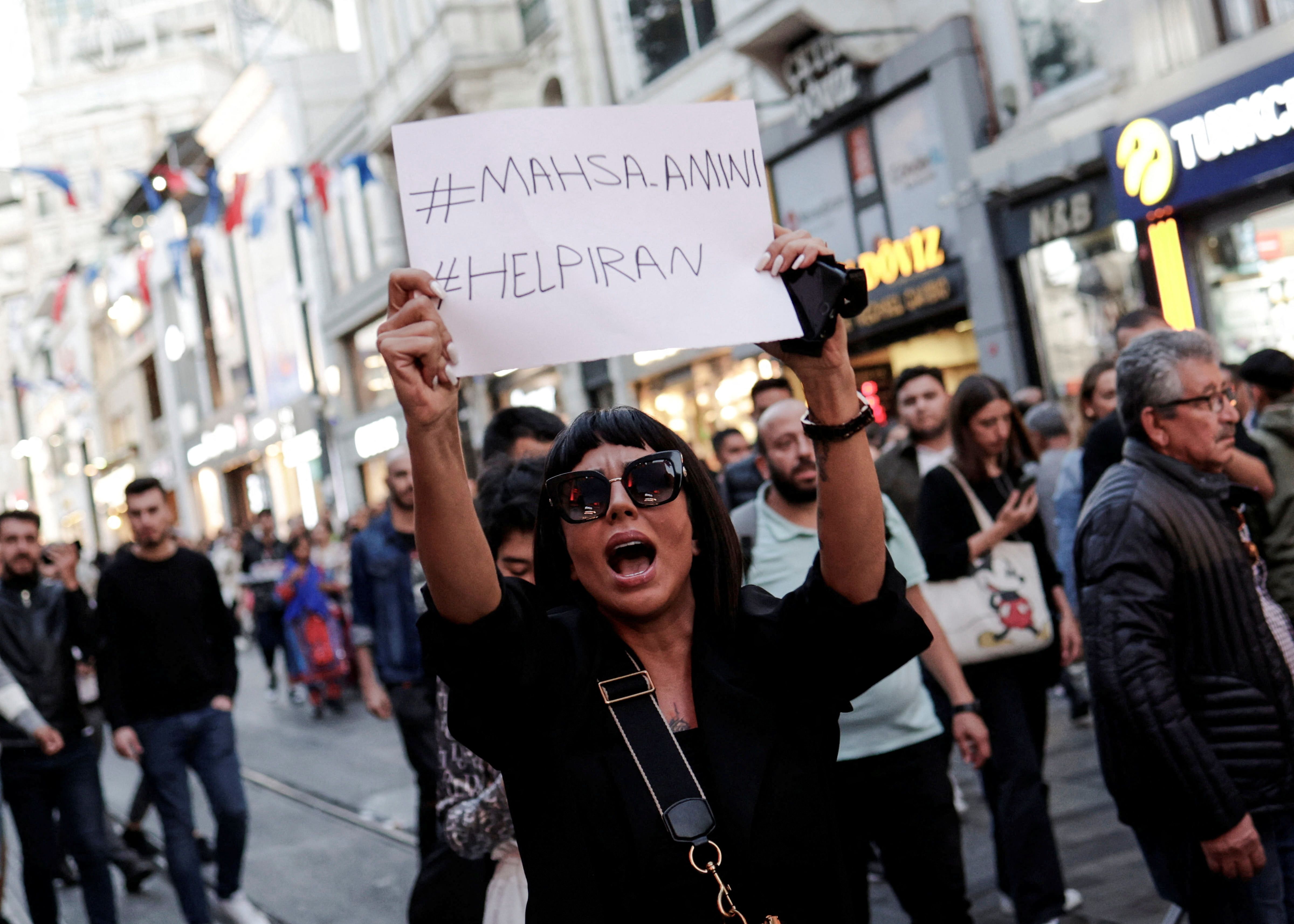 A demonstrator shouts slogans while holding up a sign during a protest in solidarity with women in Iran in central Istanbul, Turkey September 20, 2022. 