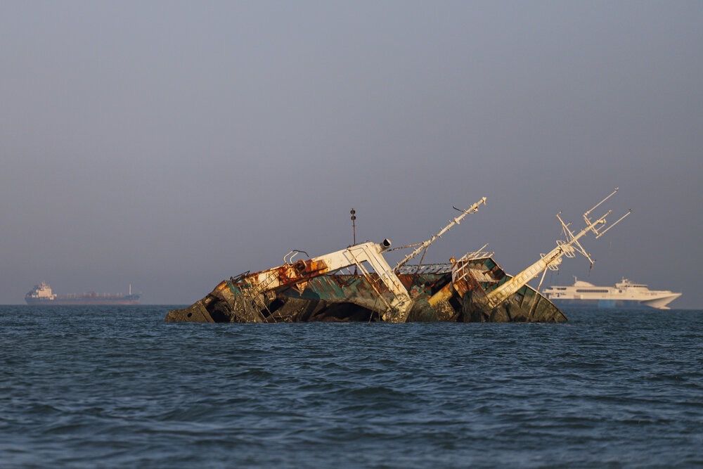 A rusting shipwreck lies partially submerged in the Strait of Hormuz, June 2026