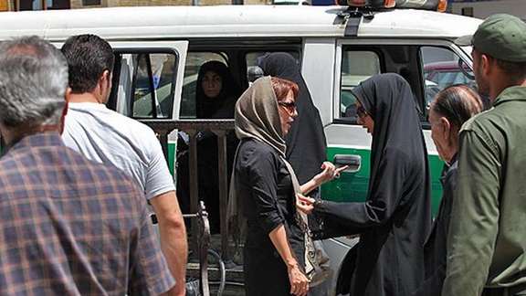 A woman with a headscarf showing part of her hair being questioned by 'chastity police' in Iran equipeed with a special van to detain women. June 2022