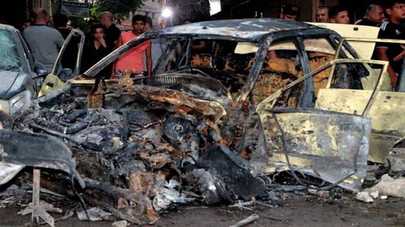 People stand near a damaged vehicle at the site of a bomb blast, outside the Sayeda Zeinab shrine city south of the Syrian capital Damascus, Syria July 27, 2023.