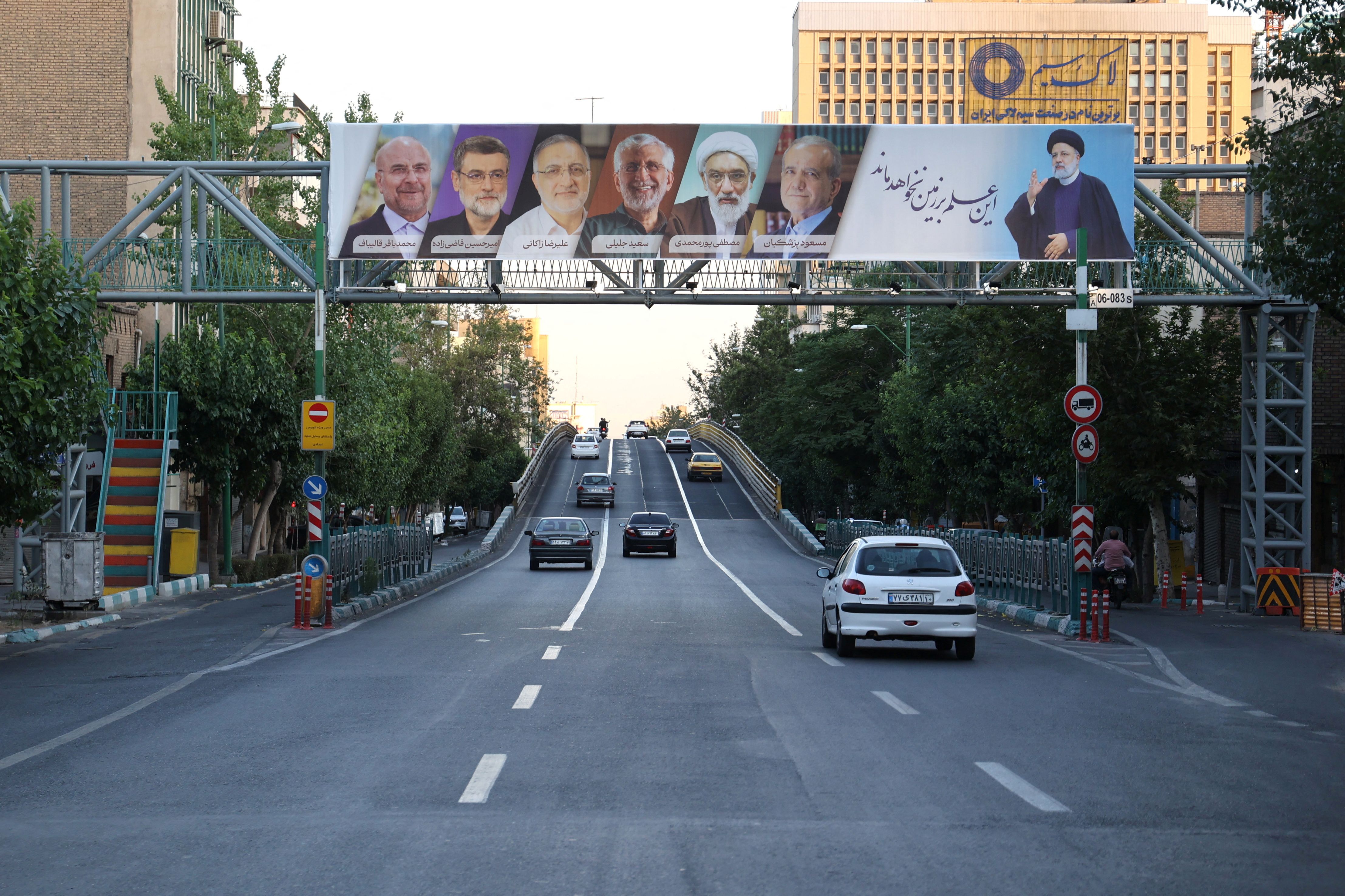 A billboard with a picture of the late President Ebrahim Raisi and the presidential candidates is displayed on a street in Tehran, Iran, June 17, 2024. 
