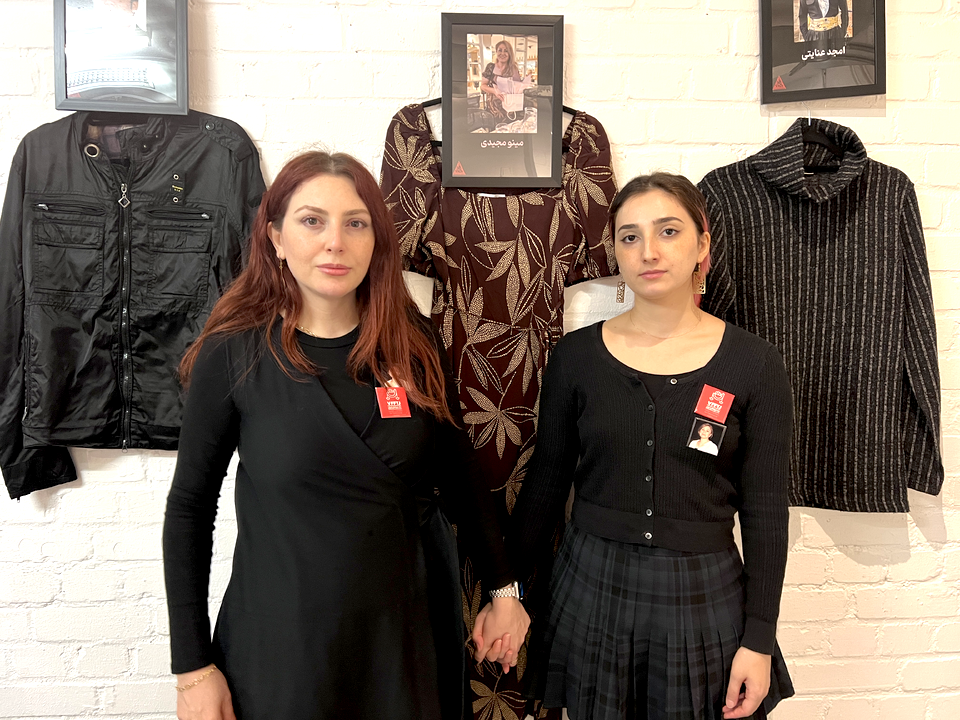 Daughters of slain protestor, Minoo Majidi standing next to her dress 
