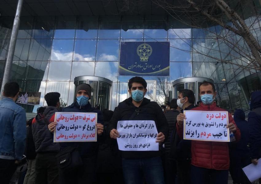 Small investors protesting outside Tehran stock exchange in 2021, holding signs calling the government "a thief".