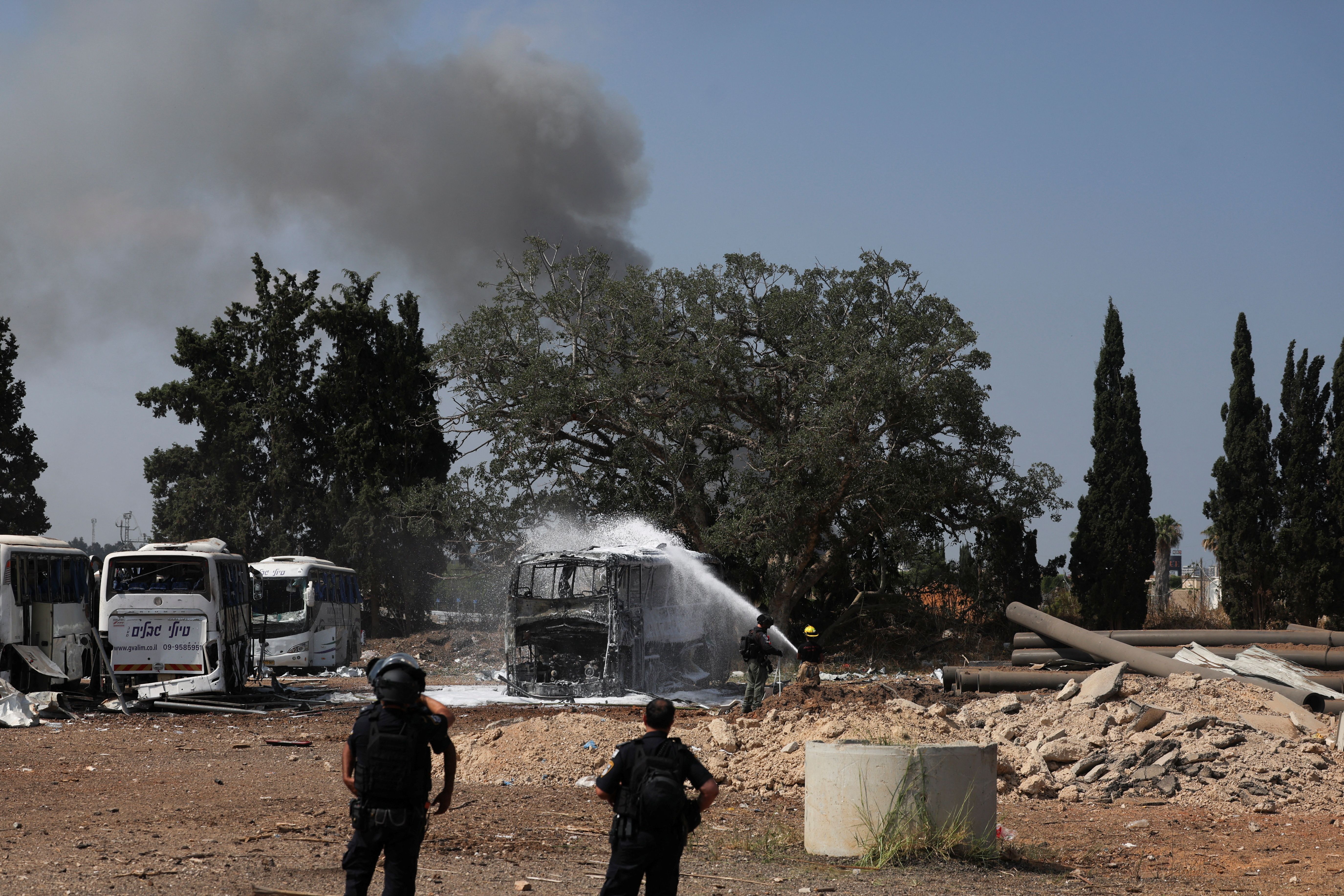 Emergency personnel spray water on a bus following a missile attack from Iran, in Herzliya, Israel, June 17, 2025.