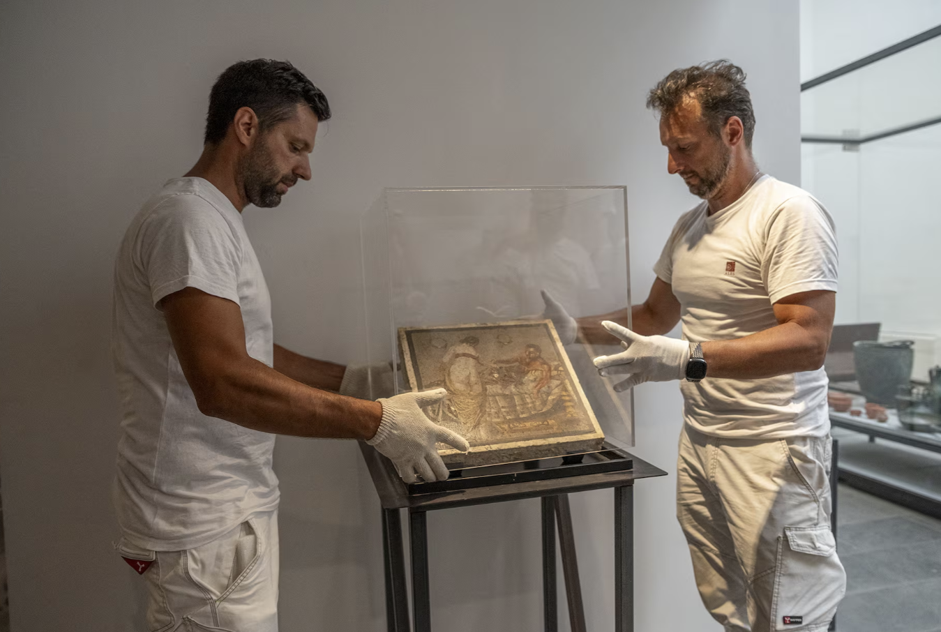 موزه‌داران در حال نصب موزاییک رومی بر دیوار موزه پُمپی