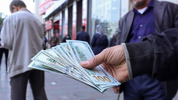 A currency dealer holding dollars on a street in Tehran
