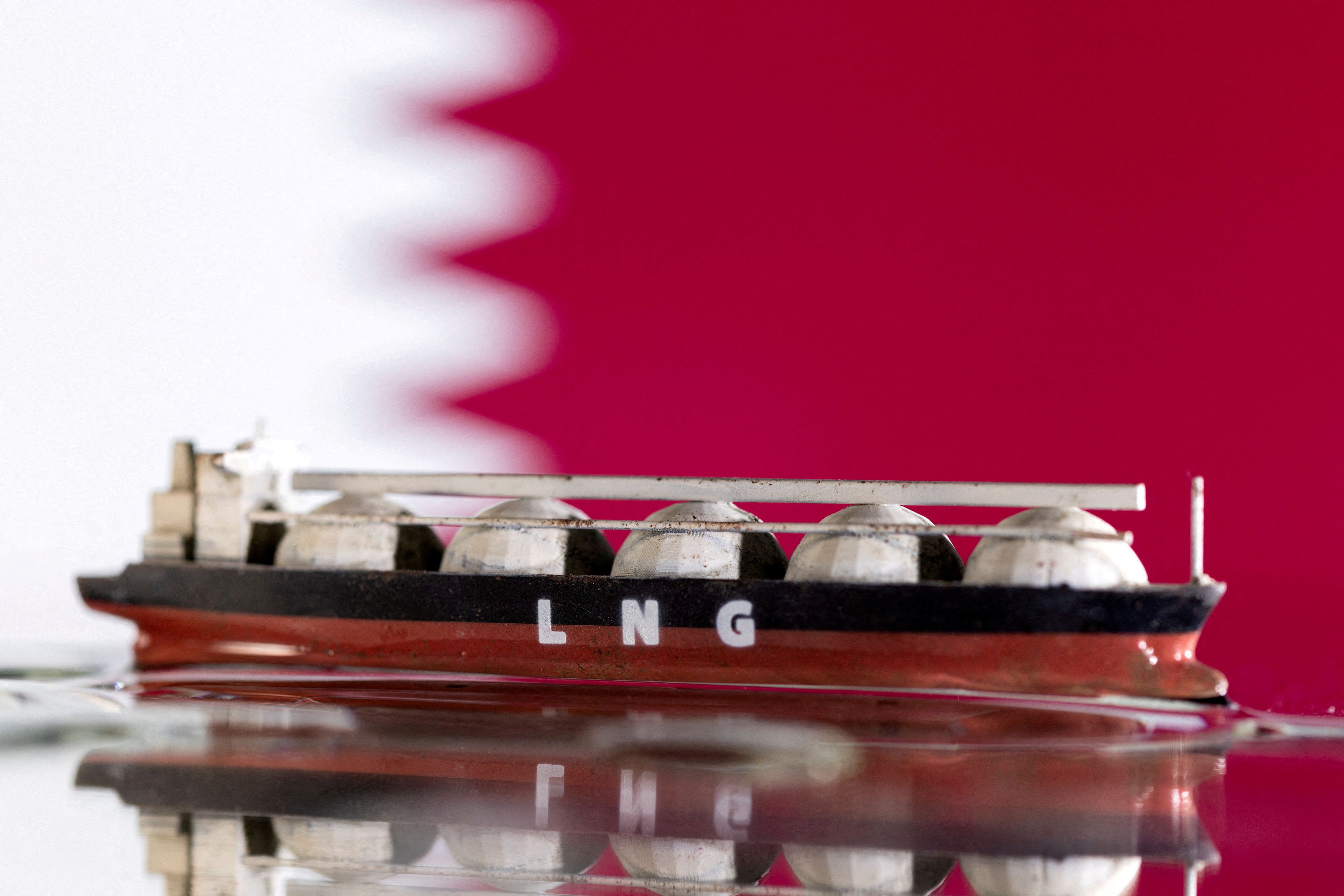 Model of LNG tanker is seen in front of Qatar's flag in this illustration taken May 19, 2022. 