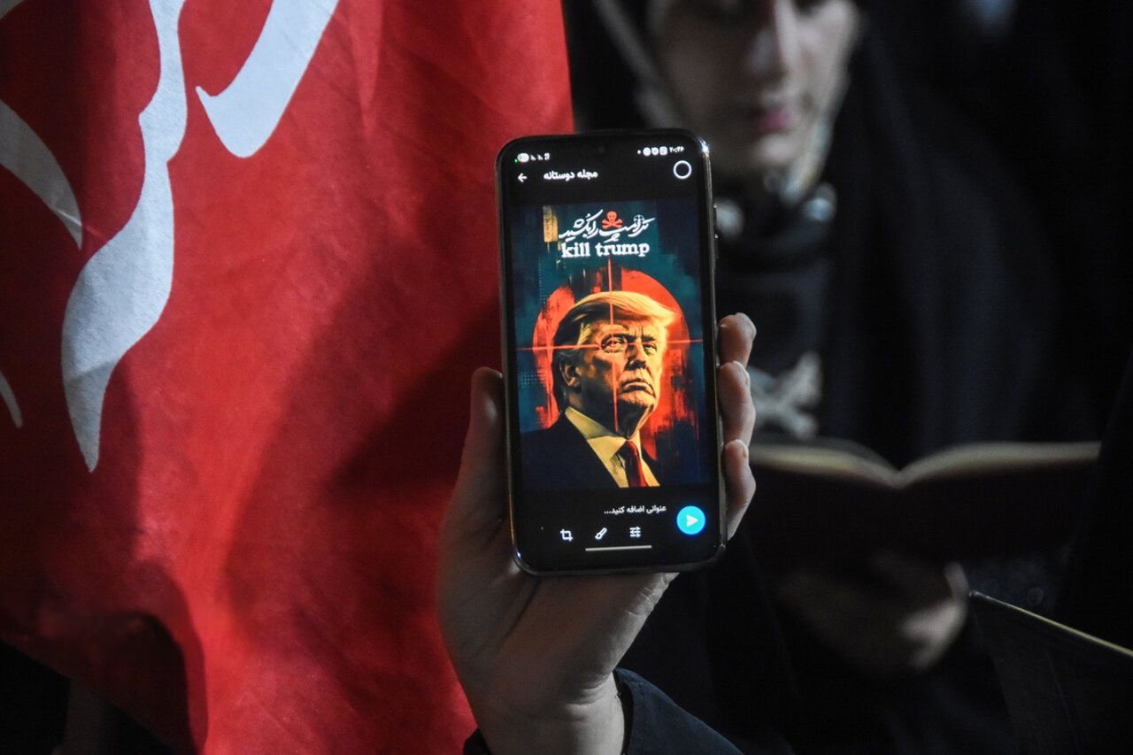 A person displays an image of US President Donald Trump in crosshairs during the funeral procession of former Supreme Leader Ali Khamenei in Iran.