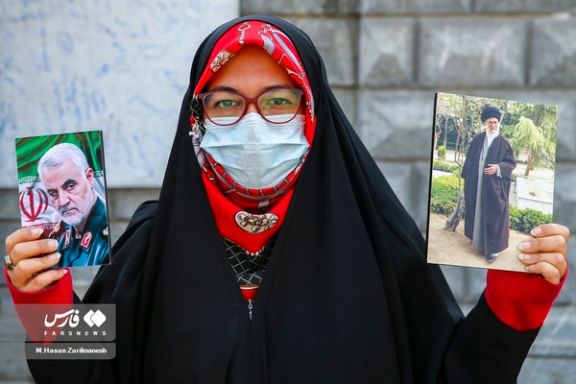 A pro-regime woman holding photos of Iran’s ruler Ali Khamenei and Qassem Soleimani, the former commander of IRGC's extraterritorial Quds Force who was killed by the US in 2020, Tehran (file photo)