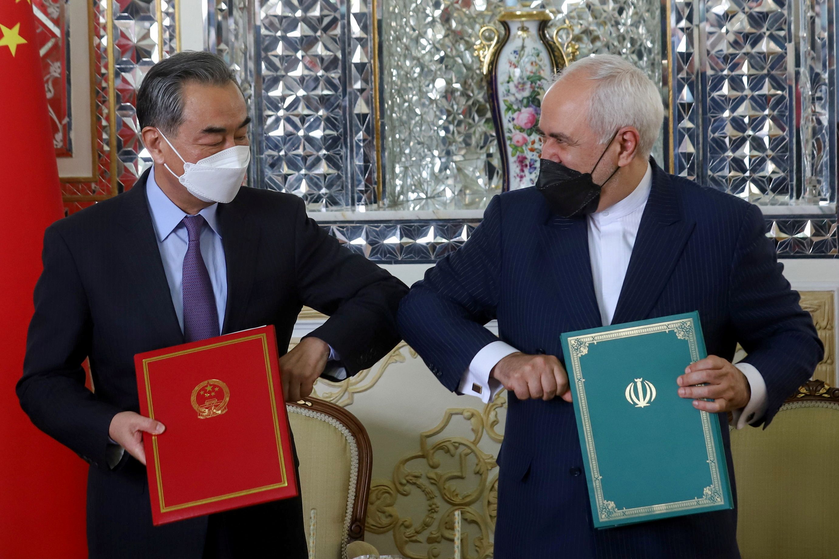 Iran's Foreign Minister Mohammad Javad Zarif and China's Foreign Minister Wang Yi bump elbows during the signing ceremony of a 25-year cooperation agreement, in Tehran, Iran March 27, 2021. 