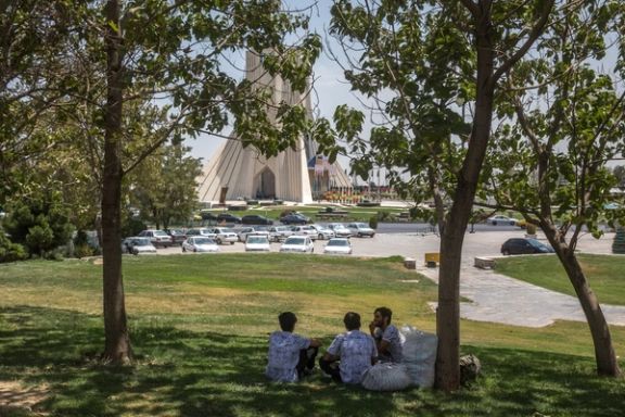 Three men sitting in the shade of a tree near Tehran's Azadi square, Iran, July 19, 2025
