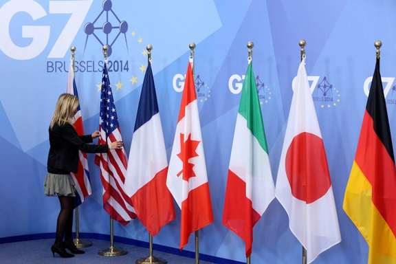 An official adjusts flags during the G7 summit at the European Council building in Brussels June 5, 2014.