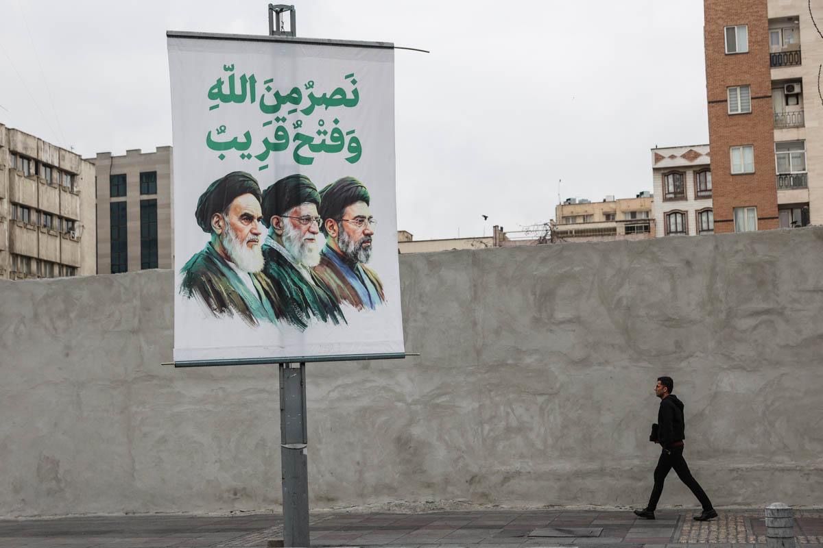  A man walks by a large banner depicting Iran's three Supreme Leaders with an Arabic verse, "victory's is God's and conquest is imminent", in Tehran, Iran, March 10, 2026