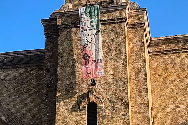 متظاهر يتسلق برج الساعة في محطة "كينغز كروس" بلندن رافعًا لافتة مناهضة للنظام الإيراني