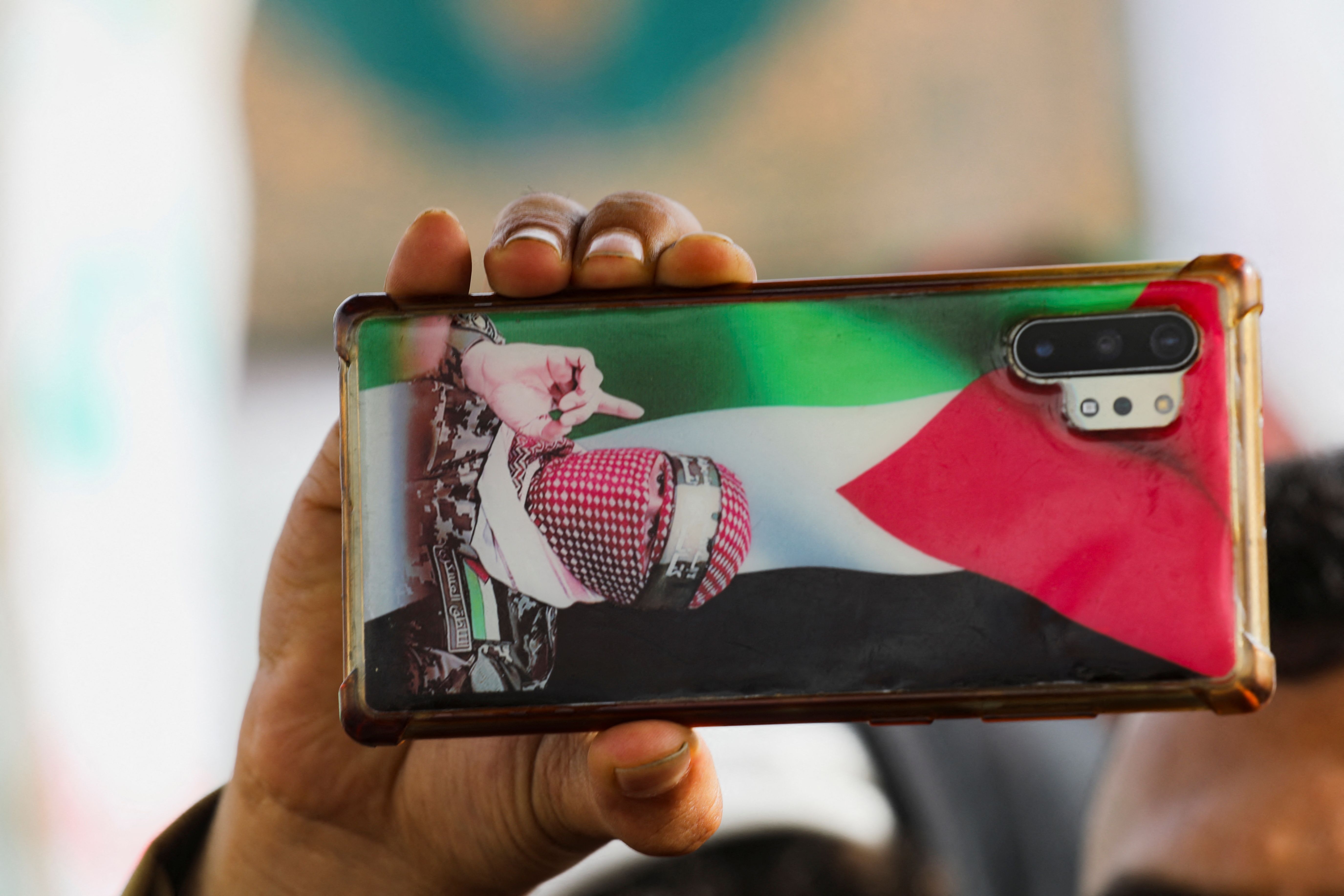 A protester holds a mobile phone with a Palestinian flag and a photo of the spokesperson for the armed wing of Hamas, Abu Ubaida, during a rally held by protesters, mainly Houthi supporters, to show solidarity with Palestinians in the Gaza Strip, in Sanaa, Yemen August 30, 2024.